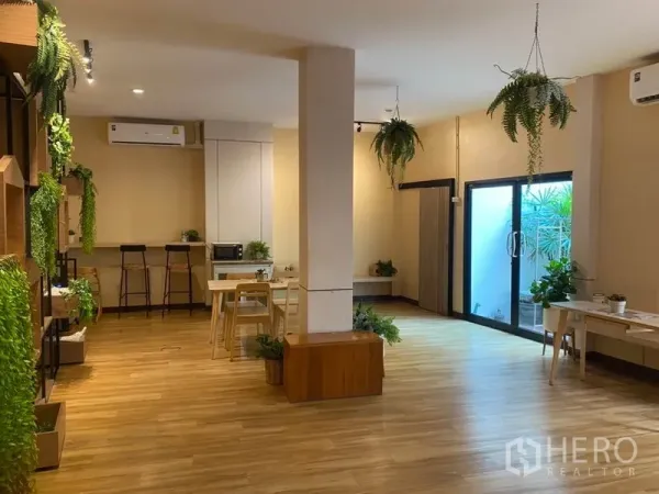 零售空间 出租在Khlong Toei, Bangkok - 开放式商铺室内，木地板、悬挂绿植、吧台座位和滑动玻璃门。