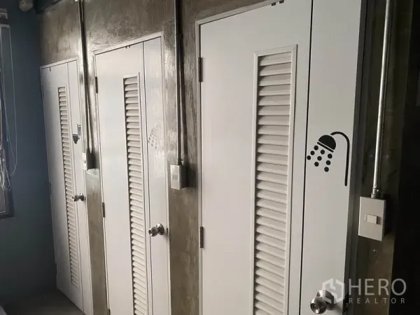 อาคารพาณิชย์ ให้เช่าในKhlong Toei, Bangkok - ประตูบานซับลมสีขาวเรียงกันของห้องอาบน้ำ ผนังปูนเปลือย