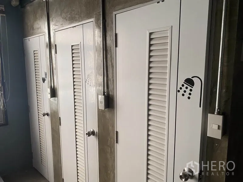 อาคารพาณิชย์ ให้เช่าในKhlong Toei, Bangkok - ประตูบานซับลมสีขาวเรียงกันของห้องอาบน้ำ ผนังปูนเปลือย