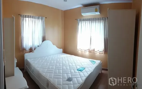 Detached House for rent in Pathum Thani - Cozy bedroom with white bed frame, wardrobe, wood flooring and air conditioning