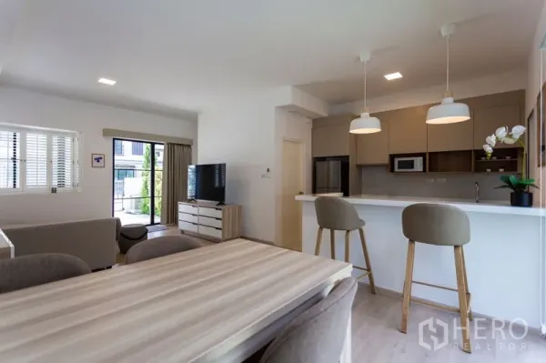 Townhouse for rent in Bang Phli, Samut Prakan - Dining area beside breakfast-bar kitchen with pendant lights, built-in cabinets and stools.