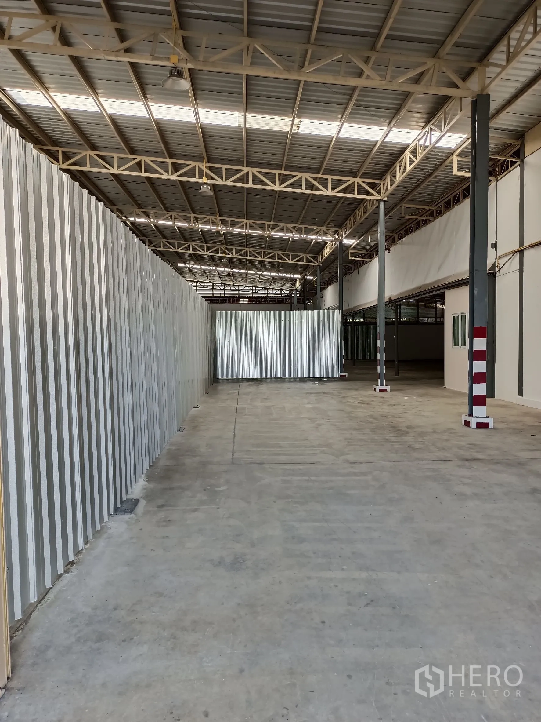 Warehouse for rent in Suan Luang, Bangkok - Long loading aisle with corrugated partitions, steel beams and overhead lighting.