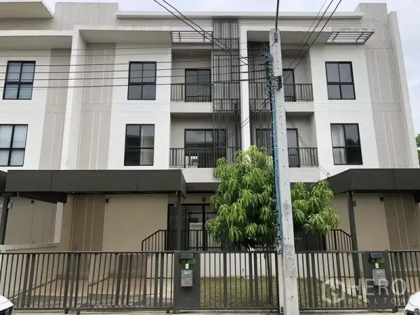 Townhouse for rent or sale in Saphan Sung, Bangkok - Modern three-storey townhouse facade with balconies, gated driveway and trees at Villa Albero.