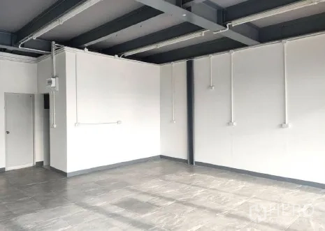 零售空间 出租在Khlong Toei, Bangkok - 店内明亮转角，灰色地砖、白墙与侧门。