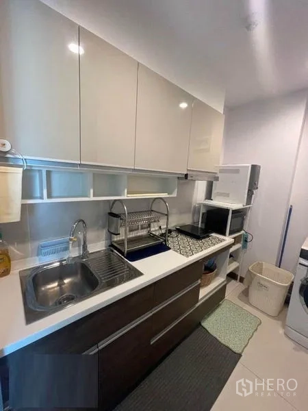 公寓 出租在Watthana, Bangkok - 紧凑型一字形厨房，亮面橱柜、水槽与台面电器。