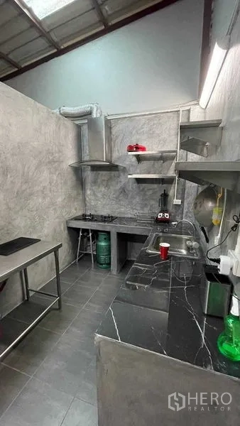 店屋 出租在Khlong Toei, Bangkok - 后方备餐厨房，设燃气灶、抽油烟机和深色台面。