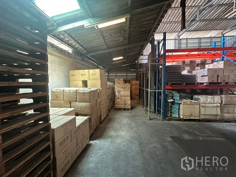 Warehouse for rent in Suan Luang, Bangkok - Storage aisle with skylights, steel shelving and boxed goods.