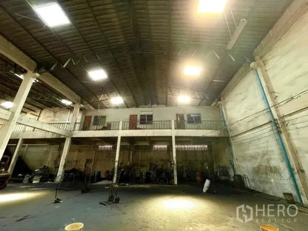 Warehouse for rent in Krathum Baen, Samut Sakhon - Spacious high‑ceiling warehouse interior with mezzanine level, concrete columns and bright industrial lighting.