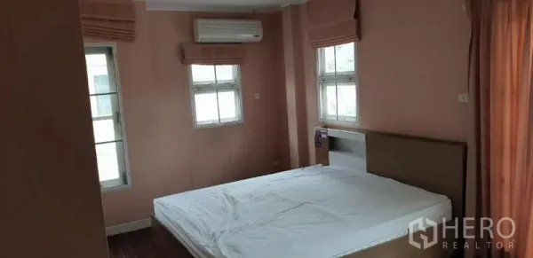 บ้าน ให้เช่าในPhra Khanong, Bangkok - ห้องนอนโทนพีช เตียงนอน หน้าต่างหลายบาน ม่าน และเครื่องปรับอากาศติดผนัง