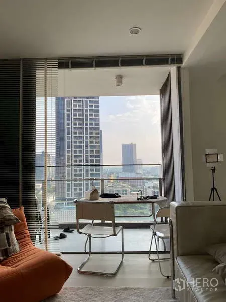 Condominium for rent - Bright living room opening to a balcony with city skyline views and a small dining set.