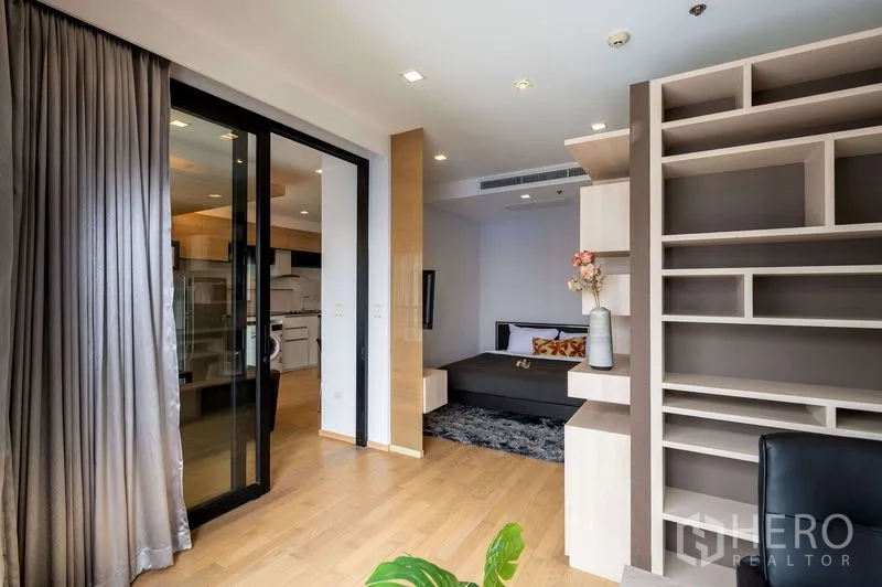 คอนโด ขายในWatthana, Bangkok - โซนทำงานพร้อมชั้นบิวท์อินขนาดใหญ่ มองไปยังห้องนอนผ่านประตูกระจกบานเลื่อน