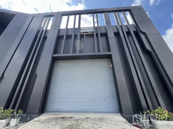 คลังสินค้า ขายในLat Krabang, Bangkok - มุมมองด้านหน้าอาคารกับฟินแนวตั้งและประตูม้วนขนาดใหญ่สำหรับขนถ่ายสินค้า.