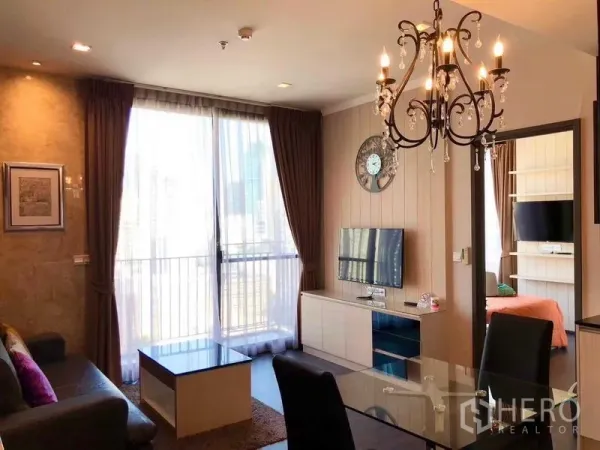 คอนโด ให้เช่าหรือขายในWatthana, Bangkok - ห้องนั่งเล่นสว่างพร้อมประตูกระจกออกระเบียง โคมไฟระย้า และทีวีติดผนัง