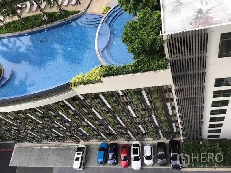 公寓 出租在Watthana, Bangkok - 平台层弧形泳池与绿化花园，上方俯瞰停车区。