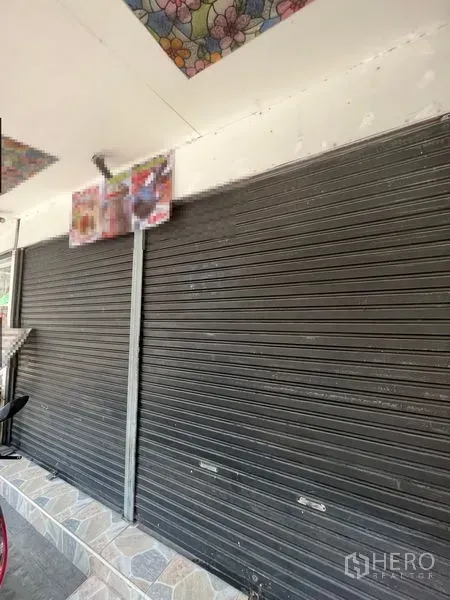 零售空间 出租在Watthana, Bangkok - 街铺临街立面，黑色卷闸门与瓷砖台阶，位于素坤逸区域。
