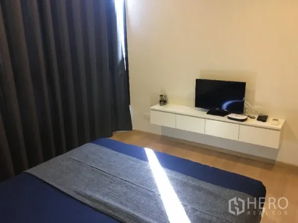 คอนโด ให้เช่าหรือขายในWatthana, Bangkok - ผนังสื่อบันเทิงในห้องนอนพร้อมทีวีจอแบนบนตู้แขวนและผ้าม่านทึบแสง.