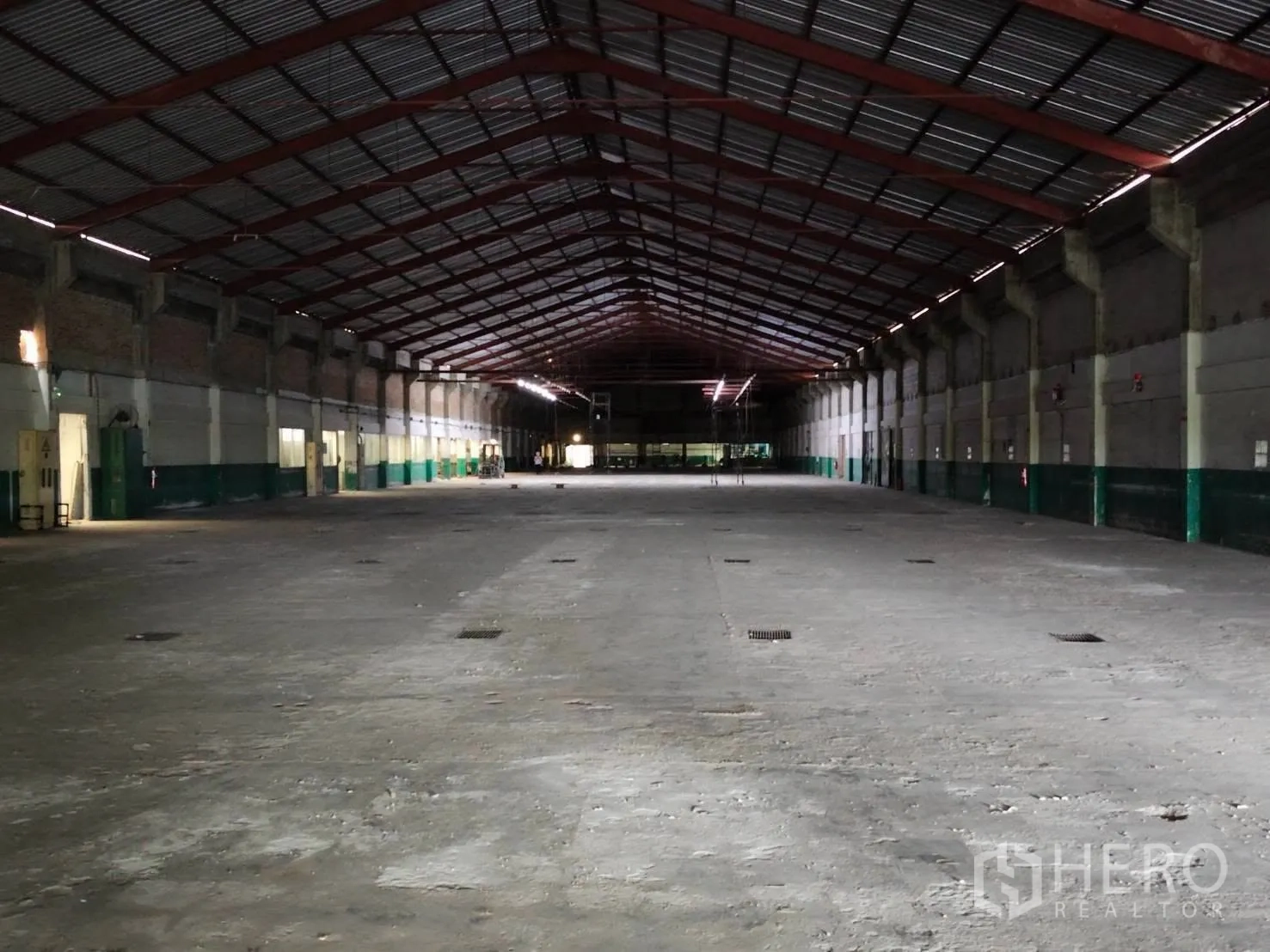 Warehouse for rent in Mueang Samut Prakan, Samut Prakan - Long gabled warehouse view with ventilation panels and floor drains.