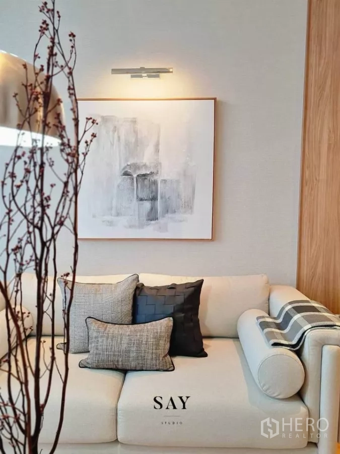 公寓 出租或出售在Khlong Toei, Bangkok - 沙发与靠垫特写，墙面抽象画与暖色壁灯。