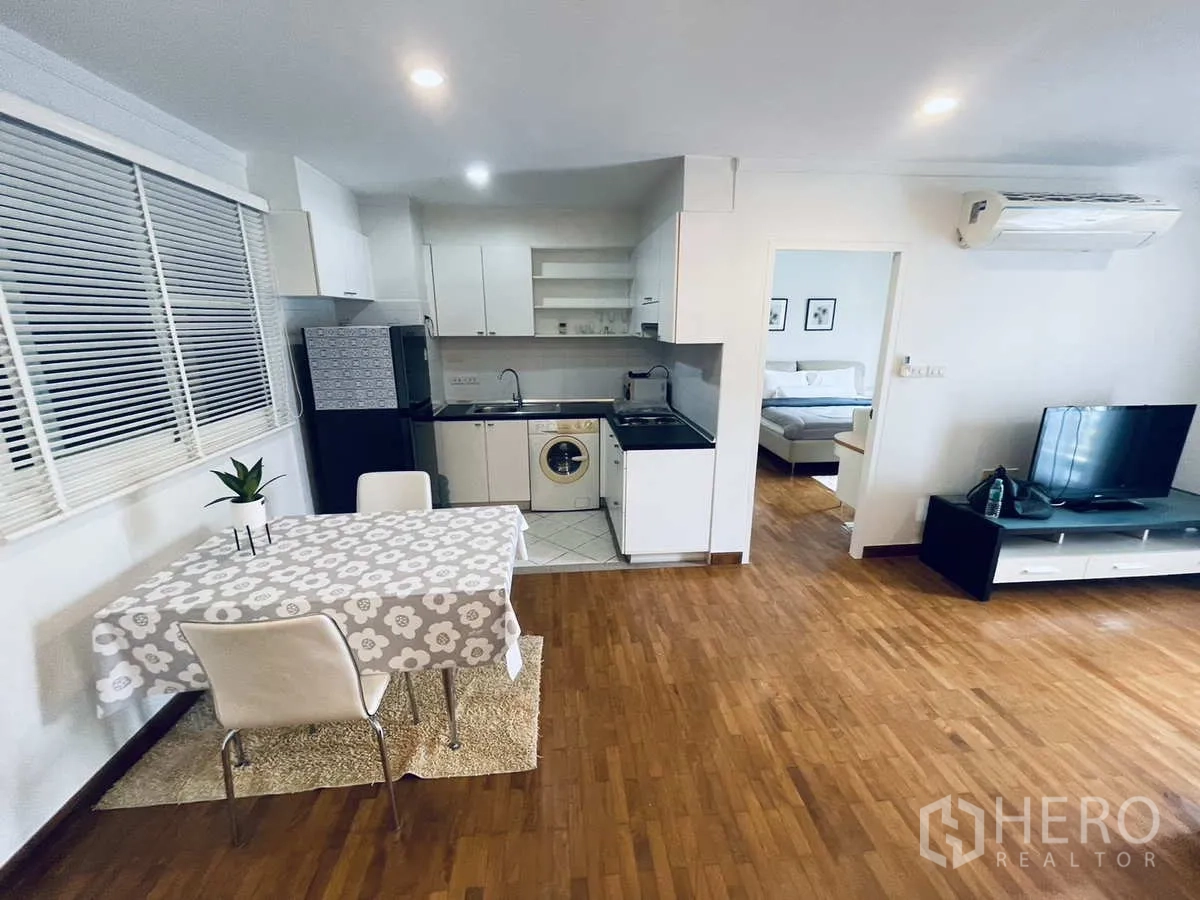 Condominium for rent in Watthana, Bangkok - Compact open kitchen with dining table, fridge, sink and washing machine.