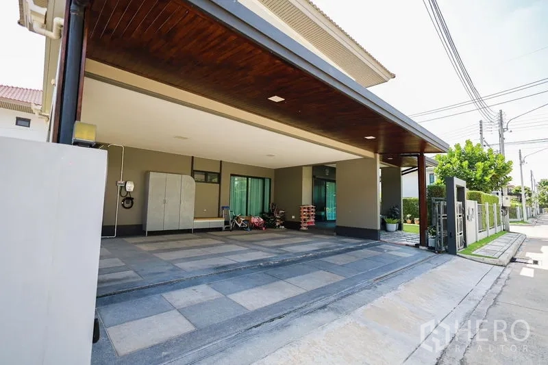 Detached House for rent or sale in Lam Luk Ka, Pathum Thani - Large covered carport for three cars with EV charger by the wall.