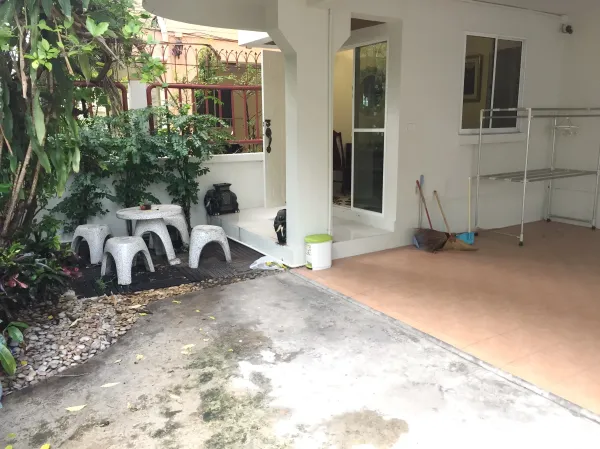 Detached House for rent in Watthana, Bangkok - Covered carport beside a small garden patio with stone table set and greenery.
