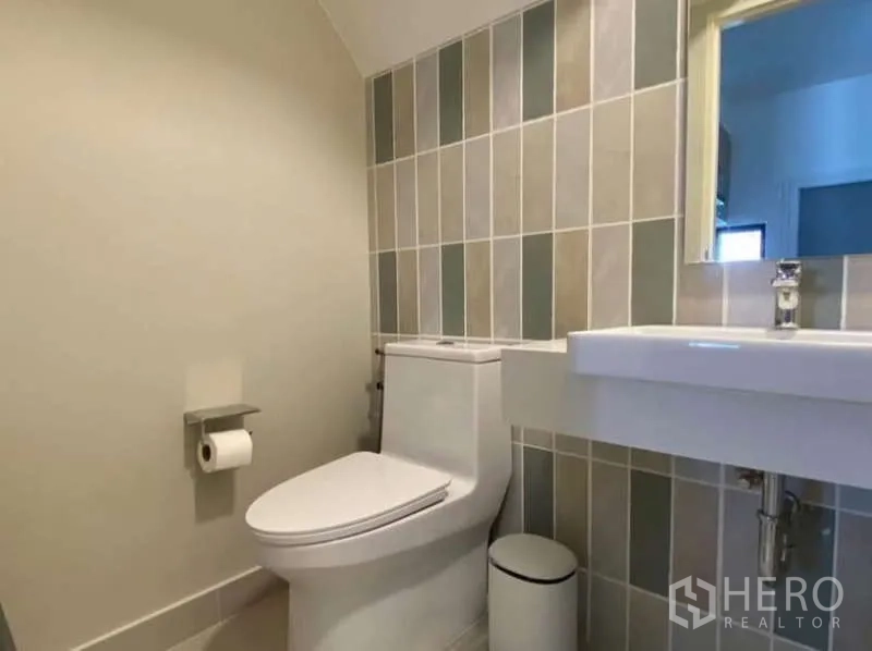 Townhouse for rent in Bang Phli, Samut Prakan - Ground-floor powder room with tiled feature wall, toilet and wall-hung sink.