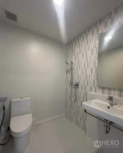 Townhouse for rent in Bang Phli, Samut Prakan - Minimal bathroom with wall-mounted shower, toilet and white basin with mirror.