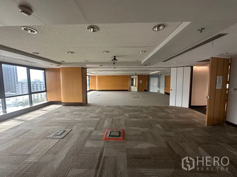 Office Space for rent in Khlong Toei, Bangkok - Open-plan workspace with floor box outlets, wood panel columns, and full-height windows over Bangkok.