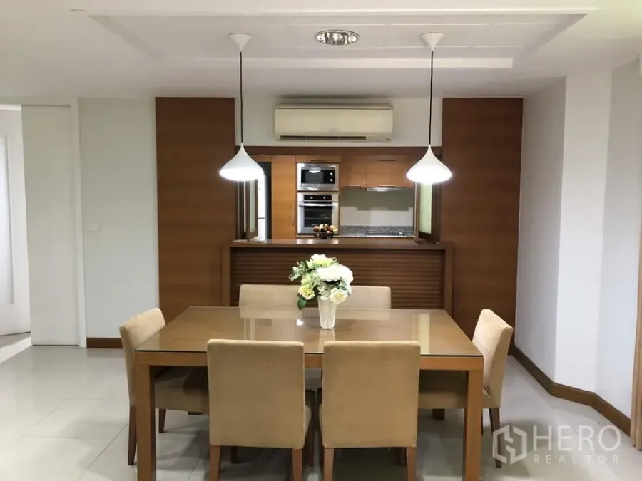 Detached House for rent in Watthana, Bangkok - Dining area with pendant lights and a six-seat table facing a wood-finished kitchen.
