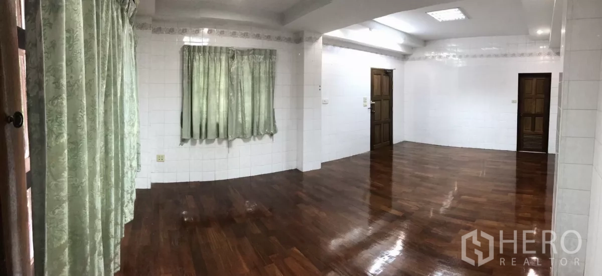 Home Office for rent in Dusit, Bangkok - Spacious room with green curtains, ceiling lights, and smooth wooden floors ready for office use.