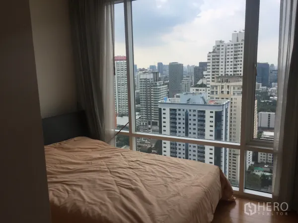Condominium for rent or sale in Watthana, Bangkok - Bedroom with large corner windows offering a panoramic view of Bangkok’s skyline.