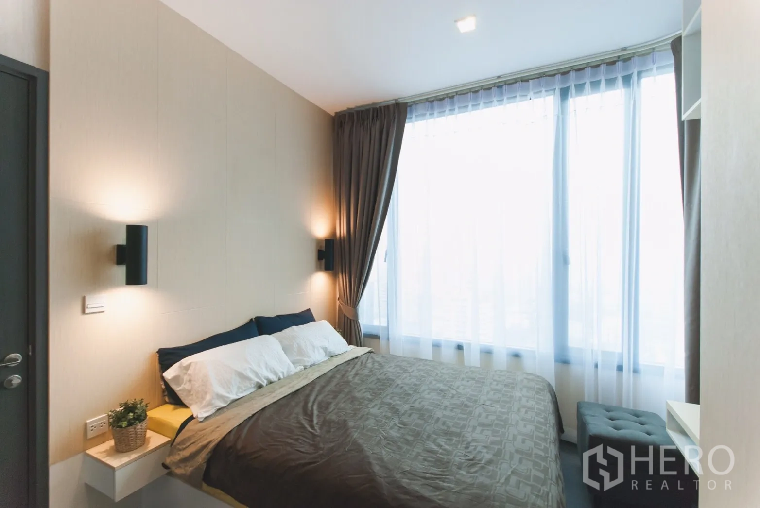 公寓 出租在Watthana, Bangkok - 明亮卧室，双人床与壁灯，大面积落地窗配纱帘。