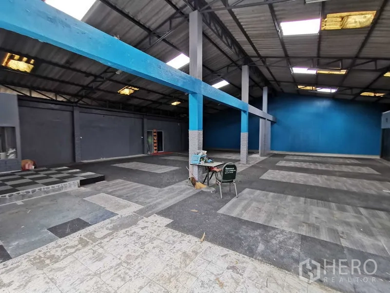 货栈 出租在Nonthaburi - 宽阔仓库地面，蓝色梁、带台阶的平台与混凝土地坪。