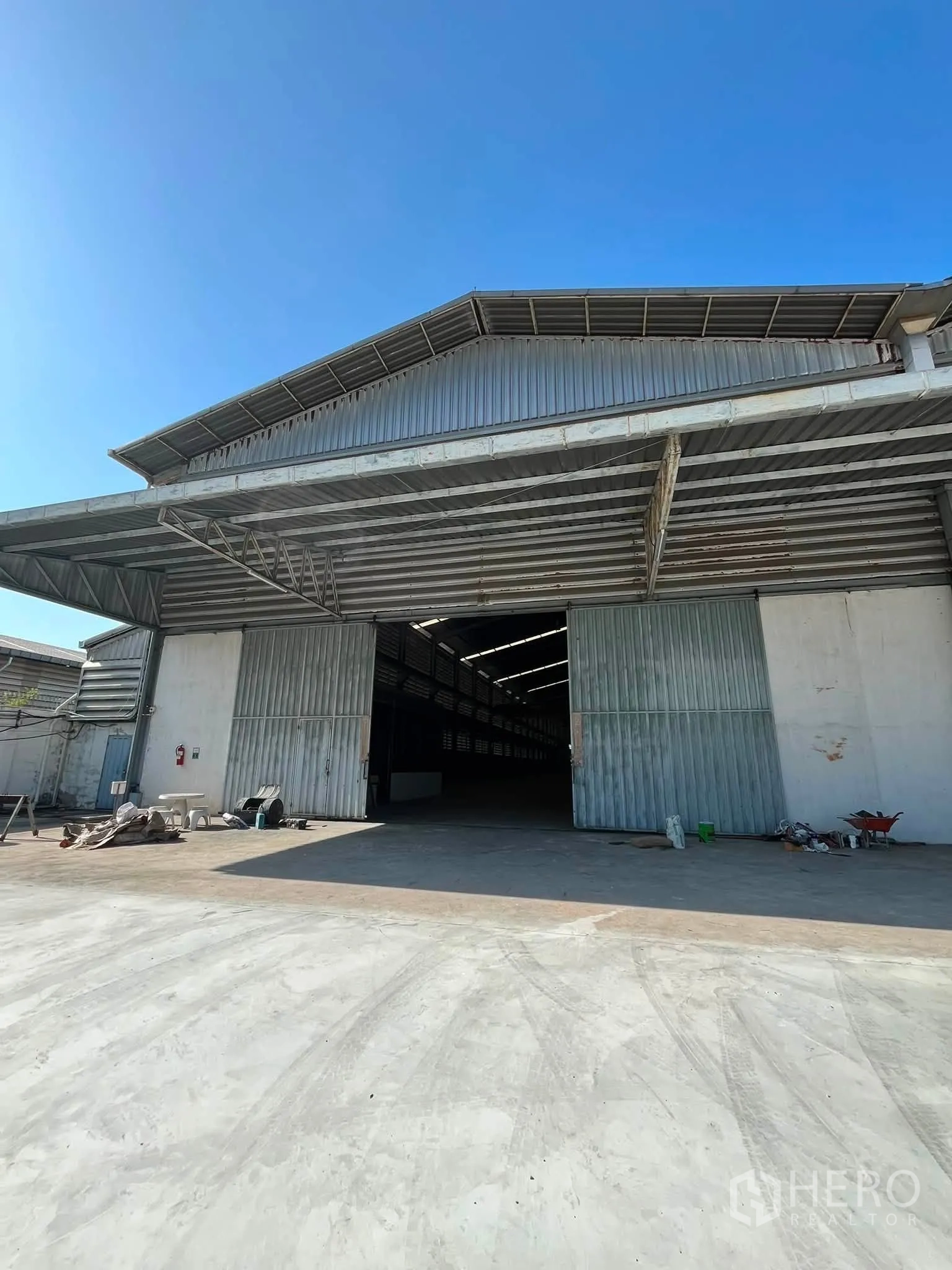Warehouse for rent in Bang Phli, Samut Prakan - Exterior facade of the steel warehouse with open sliding doors and driveway.