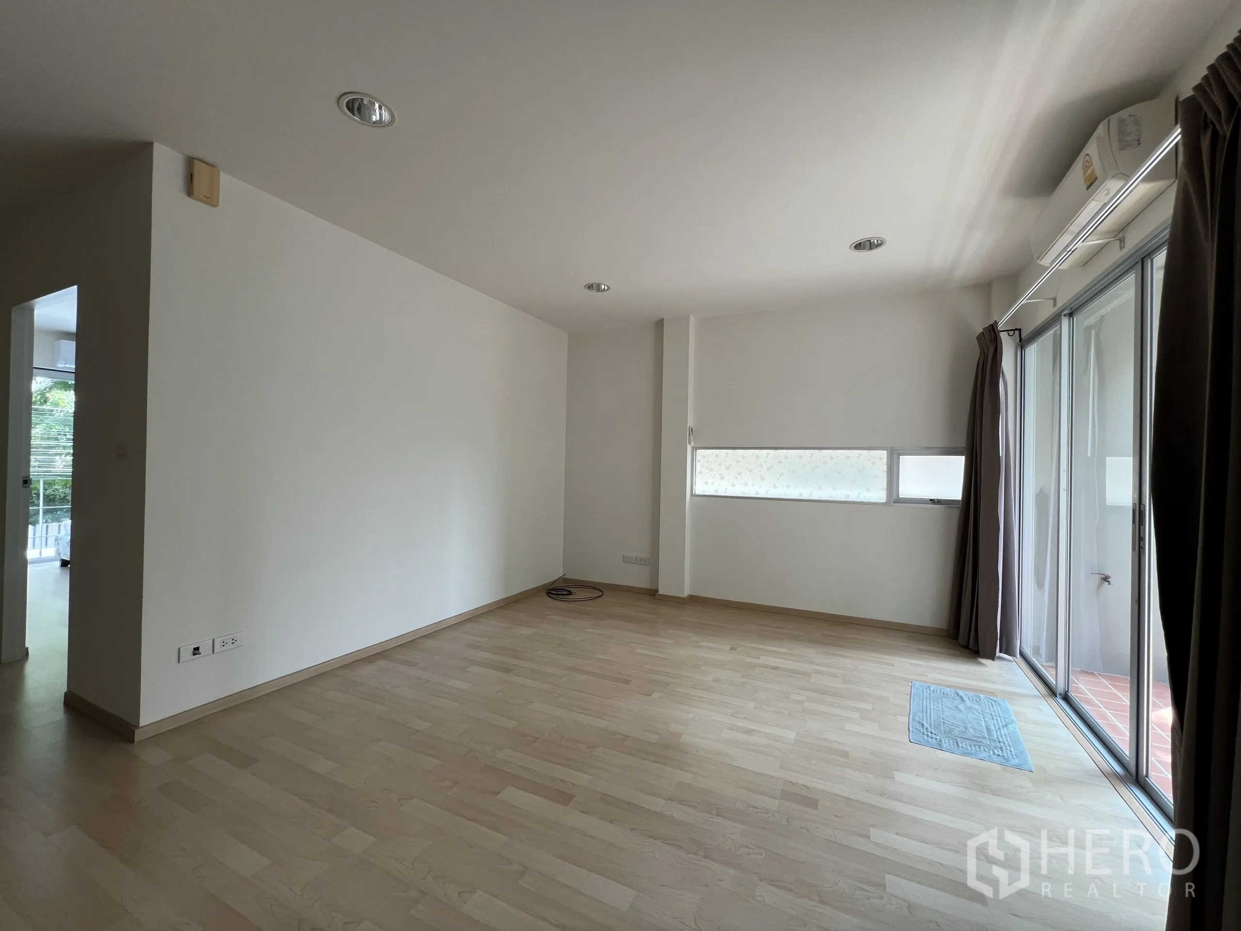 Townhouse for rent in Suan Luang, Bangkok - Bedroom with large windows, double bed, and bookshelf.