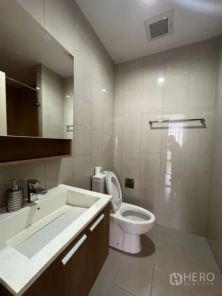 公寓 出租在Watthana, Bangkok - 现代化浴室，洗手台、大镜子与马桶，浅色瓷砖