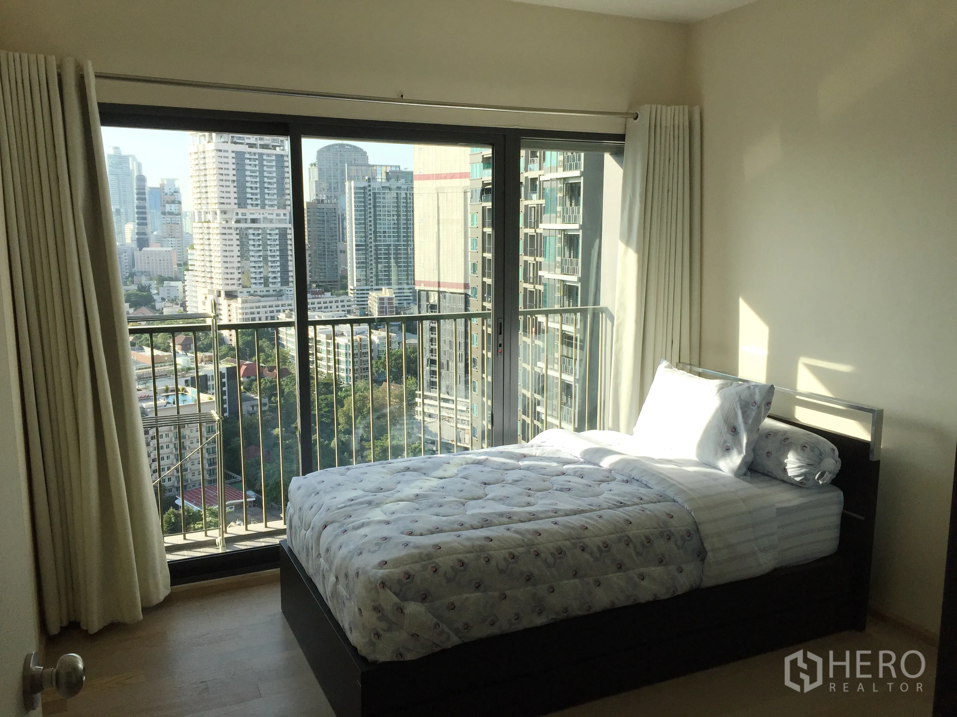 คอนโด ให้เช่าในKhlong Toei, Bangkok - ห้องนอนสว่างมีประตูกระจกบานเลื่อนและวิวสกายไลน์จากระเบียง