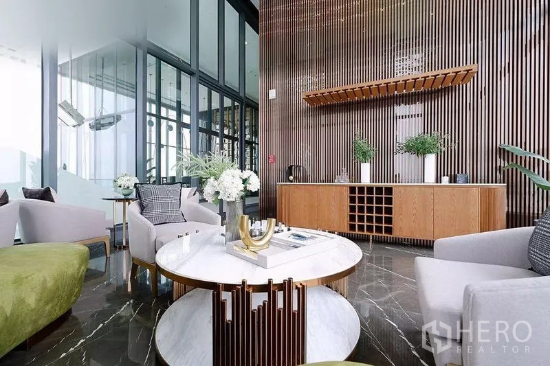 公寓 出租在Watthana, Bangkok - 曼谷公寓的天空会所，石材地面、木质格栅墙、圆形茶几与整面玻璃。