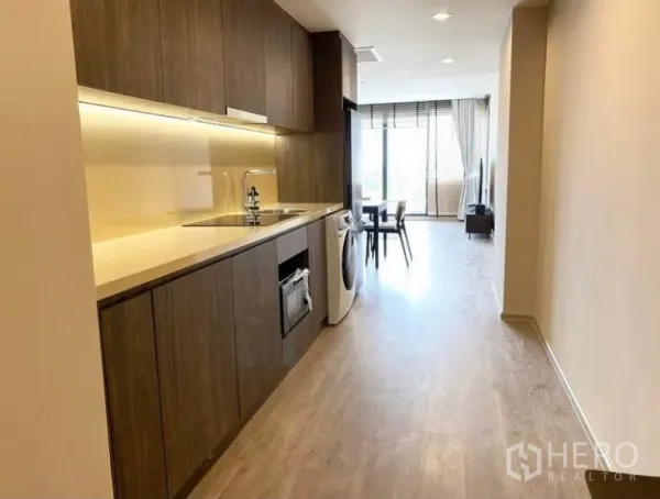 Condominium for rent in Pathum Wan, Bangkok - Long kitchen corridor leading to dining area and balcony with ample natural light.