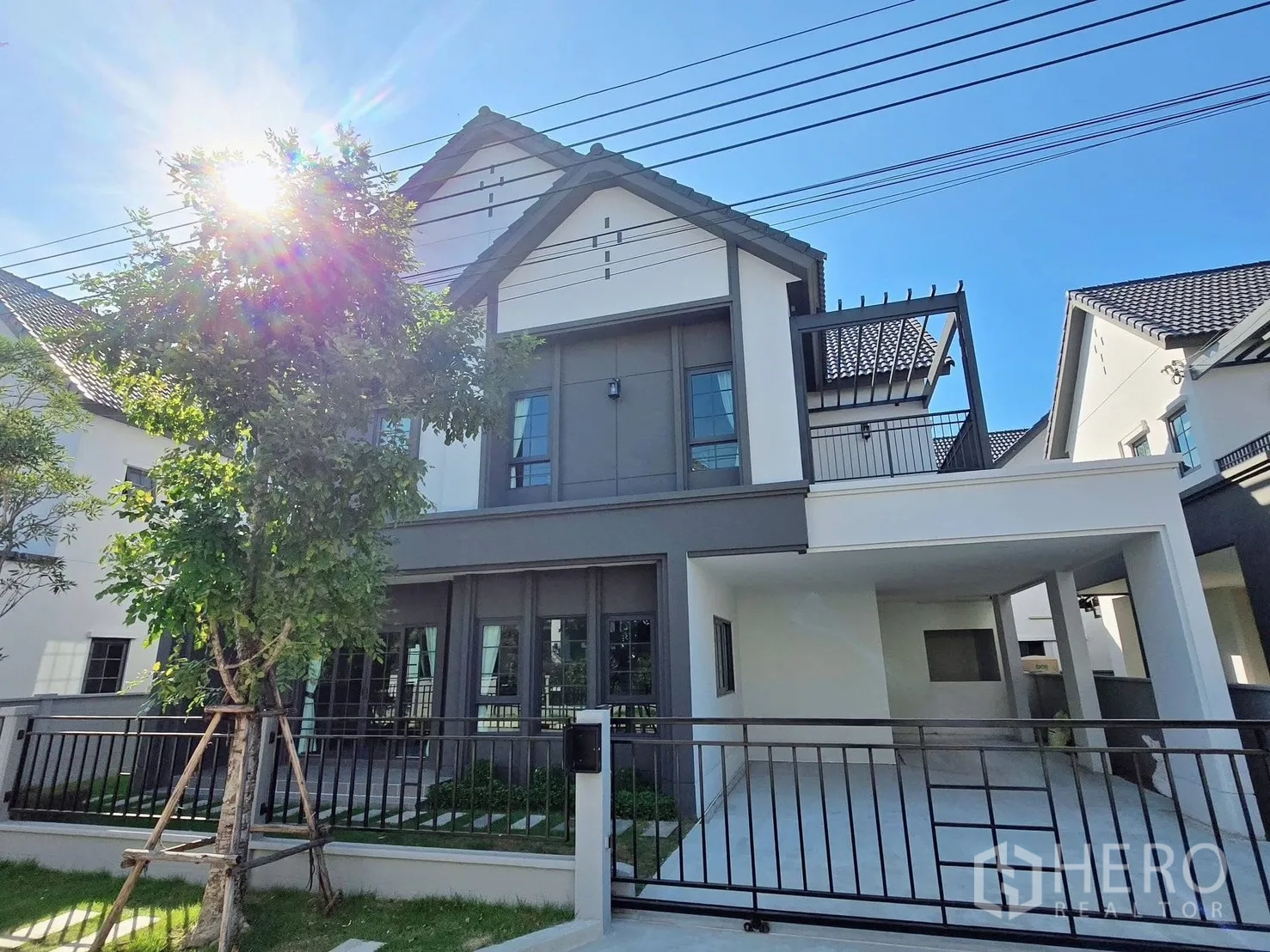 独立式住宅 for rent or sale in Bang Phli, Samut Prakan - 两层现代独立屋外立面，双坡屋顶，带车棚与前院围栏。