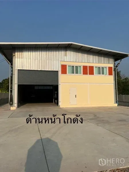 Warehouse for rent in Lam Luk Ka, Pathum Thani - Front facade of the warehouse with tall roller door, windows and a spacious concrete driveway.