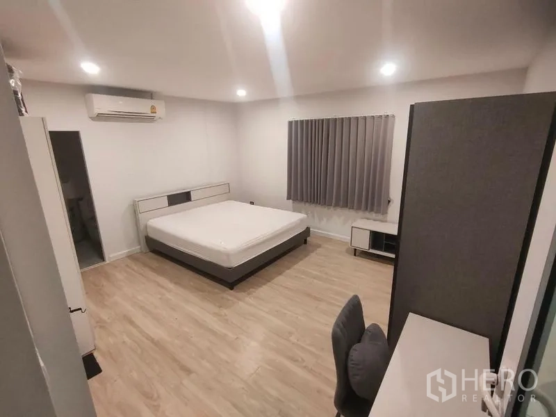 独立式住宅 出租在Prawet, Bangkok - 宽敞卧室，特大床、书桌与灰色窗帘