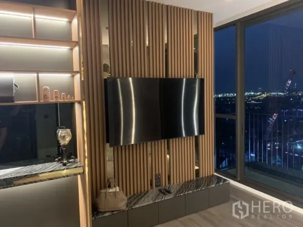 คอนโด ขายในPhra Khanong, Bangkok - ผนังทีวีลายซี่ไม้ติดระเบียง มองเห็นวิวสกายไลน์ตอนกลางคืน