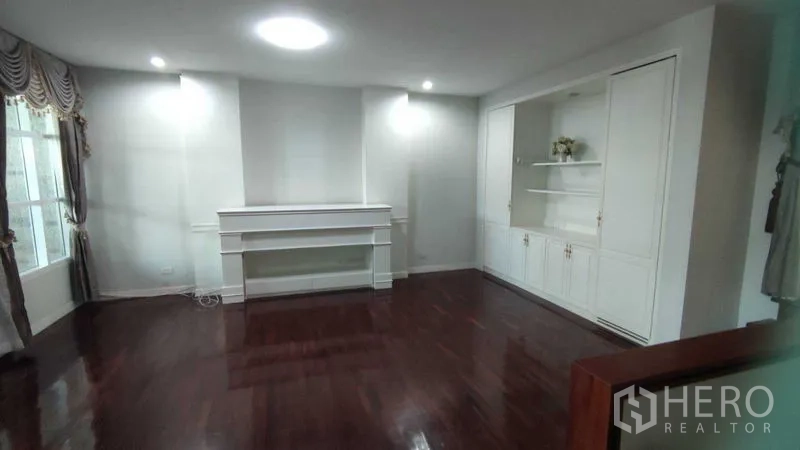 Home Office for rent in Watthana, Bangkok - Sitting room with polished wood floor, white built-ins and display shelves.