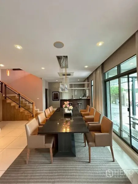 Detached House for sale in Bang Lamung, Chon Buri - Open dining room with long table for eight, pendant lights and wood staircase.
