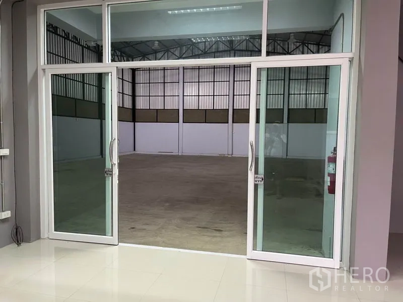 Warehouse for rent in Bang Kapi, Bangkok - Glass double doors opening from the office to a high-ceiling warehouse space.