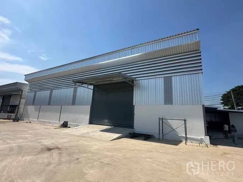 Warehouse for rent in Bang Bua Thong, Nonthaburi - Covered loading bay with roll-up door and concrete ramp at the warehouse entrance.