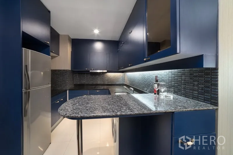 คอนโด ให้เช่าหรือขายในPathum Wan, Bangkok - ครัวรูปตัวยู ตู้สีน้ำเงิน เคาน์เตอร์หินแกรนิต และเคาน์เตอร์บาร์