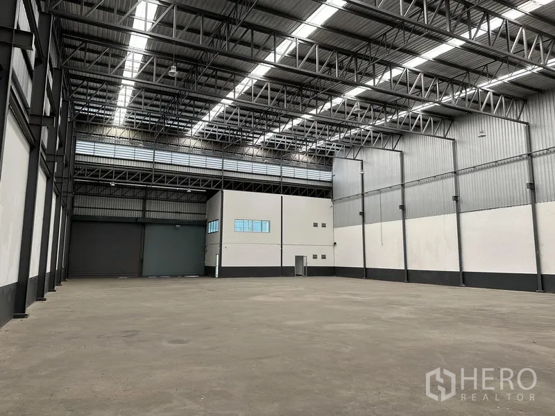 Warehouse for rent in Samut Prakan - Wide-angle view of warehouse bay with high roof, steel beams, and smooth floor.