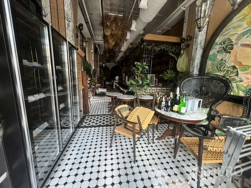 零售空间 出租在Watthana, Bangkok - 纵深咖啡馆式空间，冷藏展示柜、藤椅、小圆桌与悬挂装饰点缀。